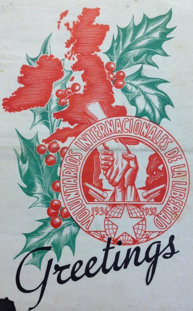 A Christmas card with an image of the British Isles and some holly and the symbol of the "voluntarios internacionales de la libertad", with the word "greetings" written at the bottom.